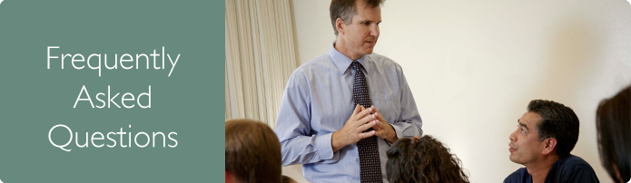 Frequently Asked Questions. Student in a classroom talking to a professor.