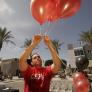 Student setting up red balloons