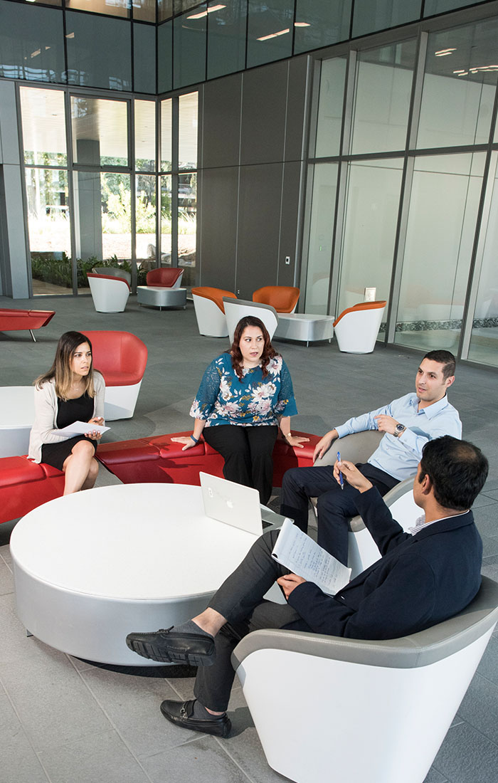 A team of professionals in an office setting, conversing around a table about potential program options.