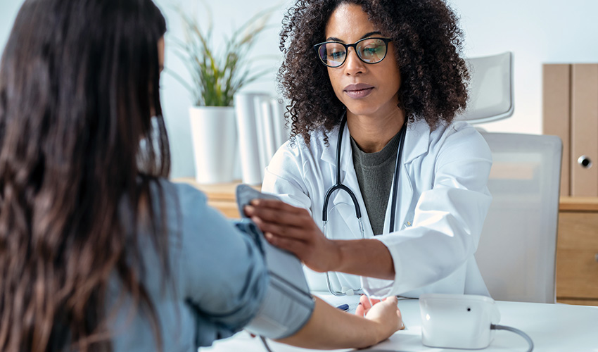 A woman has her blood pressure checked by a doctor.