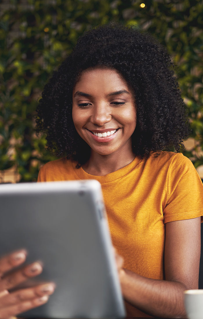 A CSUN student smiles while engaging with a tablet computer, showcasing a moment of joy and technology use.