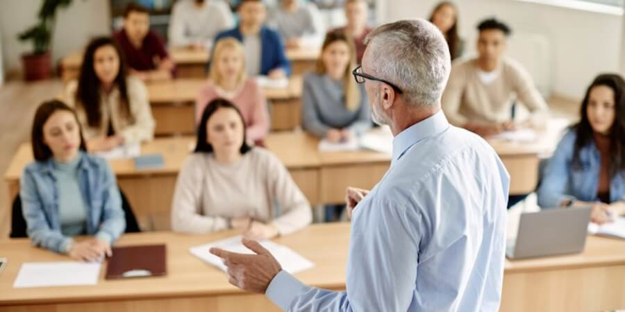 A community college professor delivers a lecture in front of a classroom full of students.