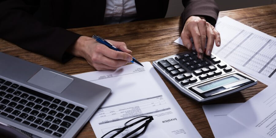 A tax director reviews documents using a calculator.