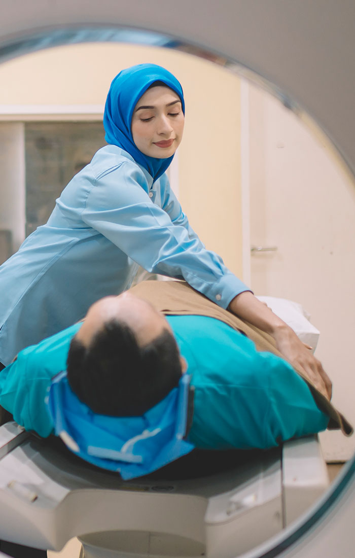 Woman in a blue scrubs preparing a patient for a scan.