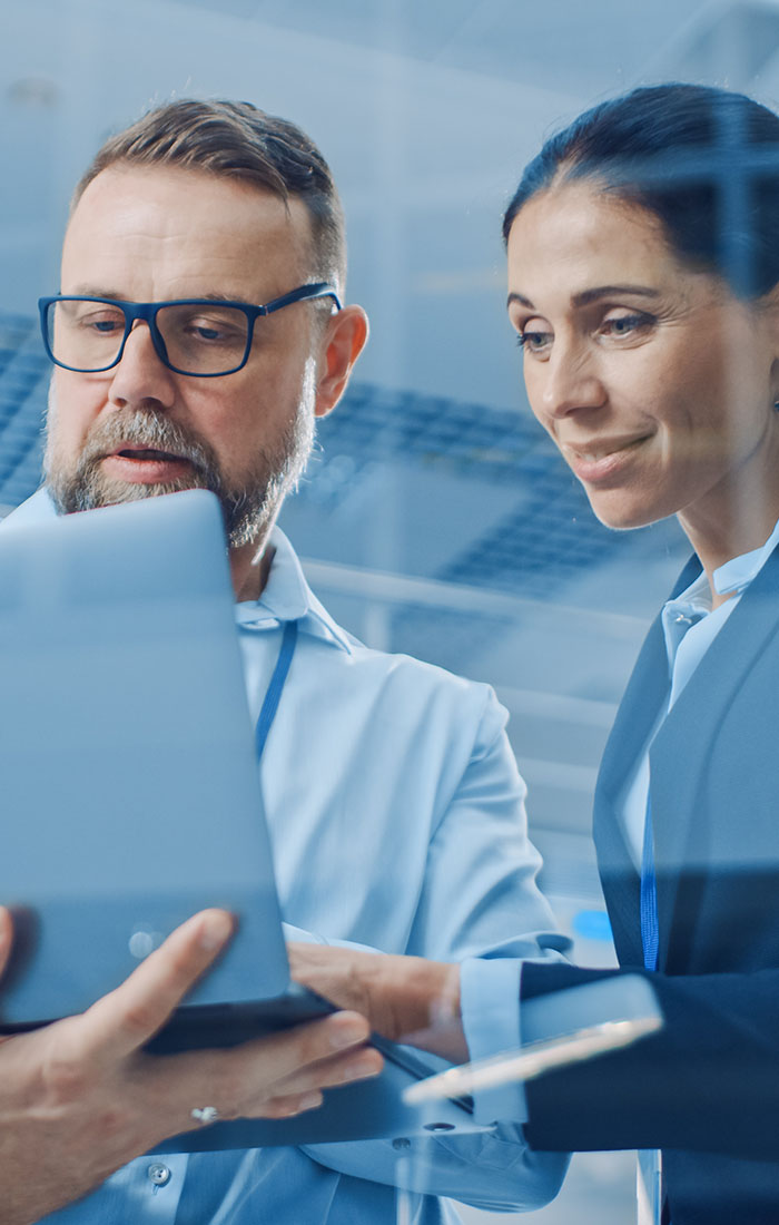 Two engineers, male and female, are looking at the laptop screen.