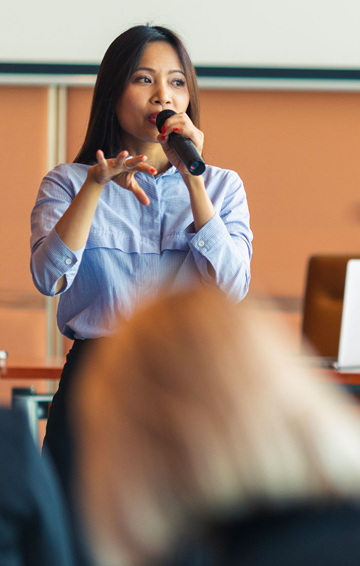 A young female presenter talking to the audience.
