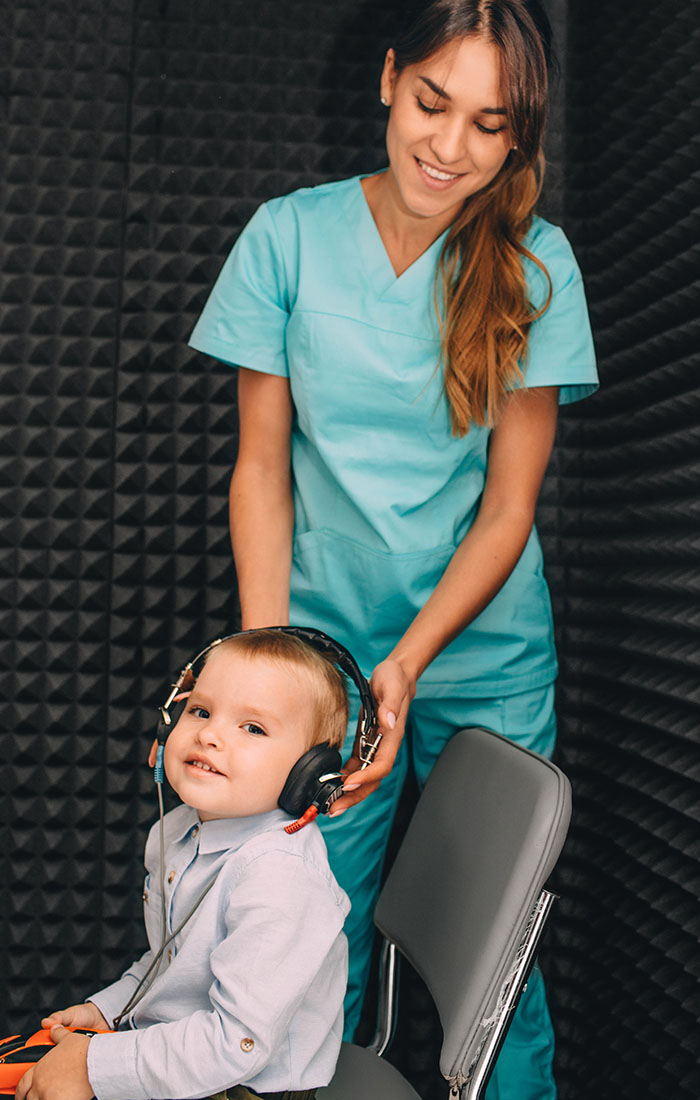 Audiologist prepares a child for hearing exam.