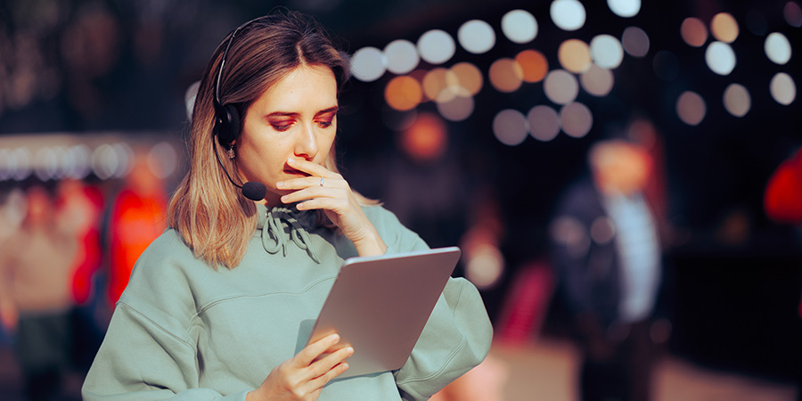 An event manager talking on a headset looking at a tablet.