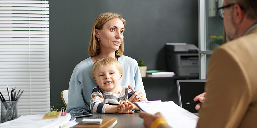 A social worker meets with a client holding an infant.