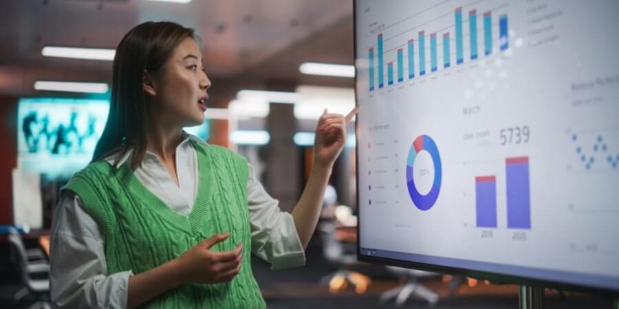 A data scientist uses a data visualization dashboard displayed on a monitor to explain their findings.