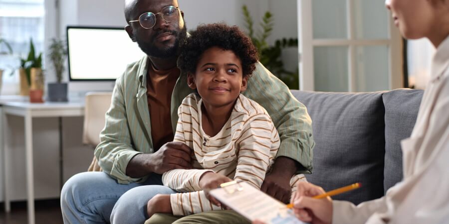 a social worker evaluating a boy sitting on a couch