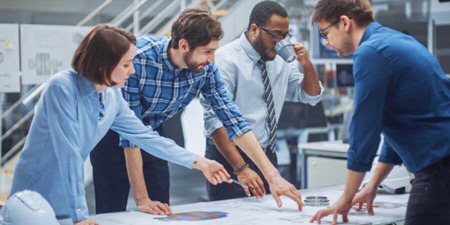 Members of an engineering team review project plans around a table