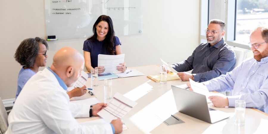Members of a healthcare data analytics team meet with hospital administrators.