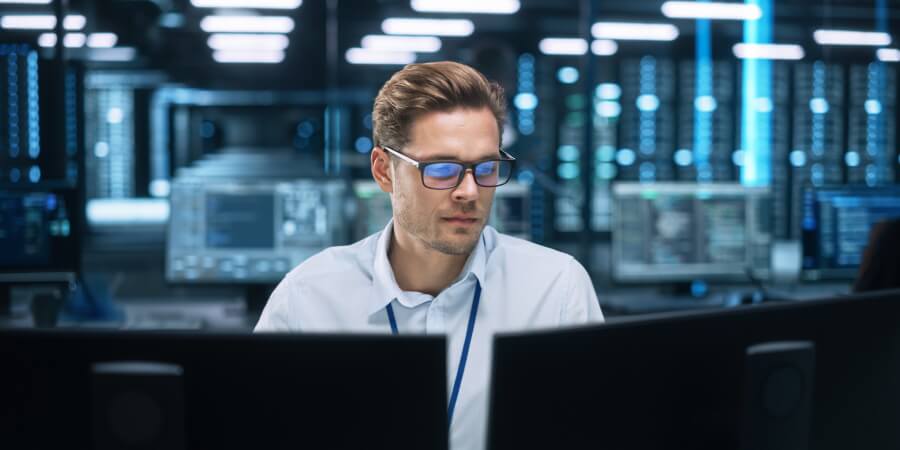 A data engineer is surrounded by computers in an office setting.
