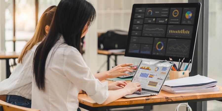 Two healthcare data analysts work on a data visualization dashboard.