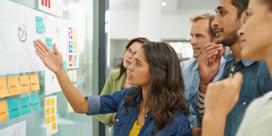 Innovation consultants brainstorm ideas using a glass board.