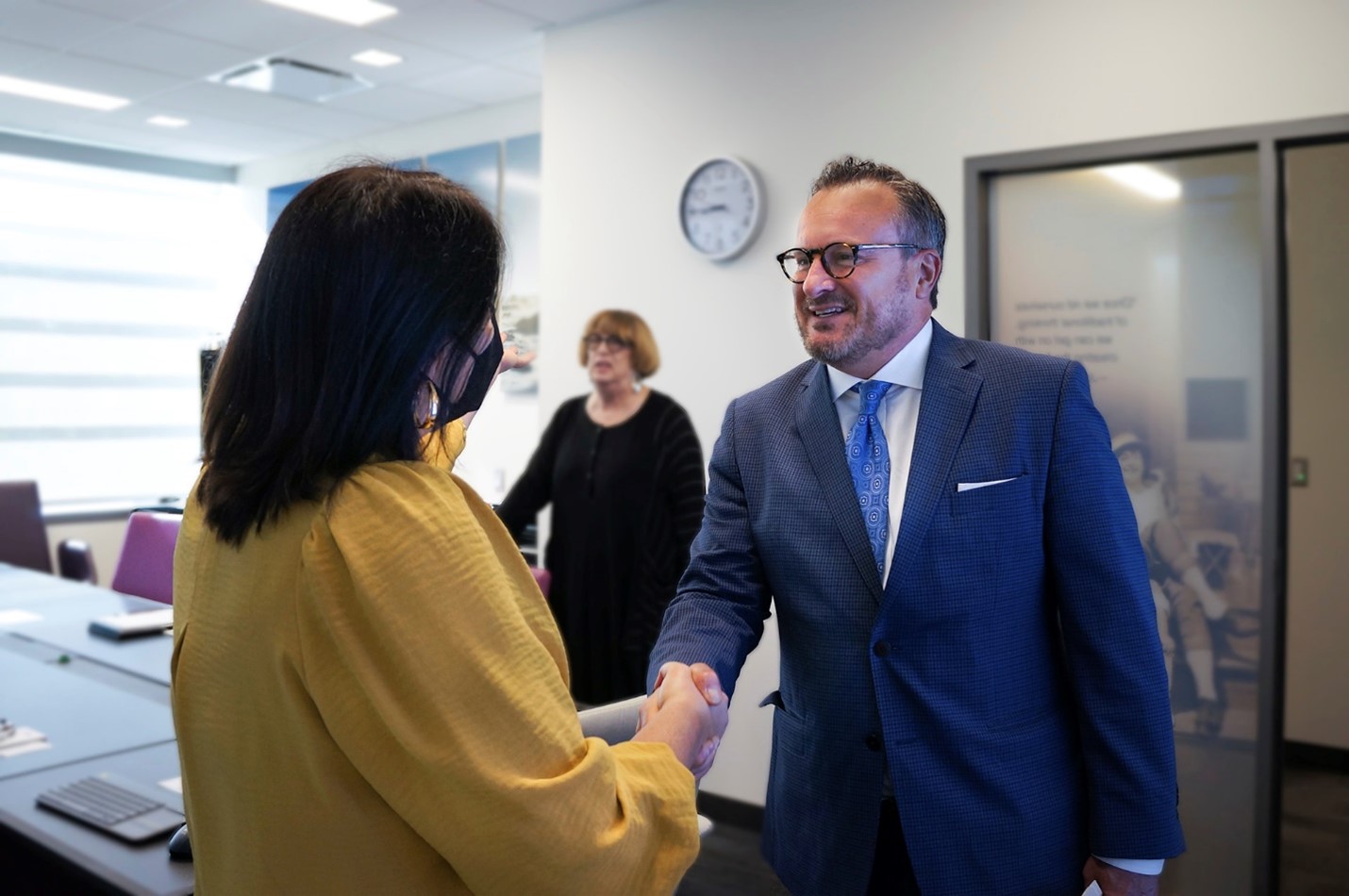 Bradley J. Cook, President of the American University of Bahrain, greets Vanessa Andrade, Director of International Programs and Partnerships, as Joyce Feucht-Haviar, Dean of the Tseng College, looks on. 