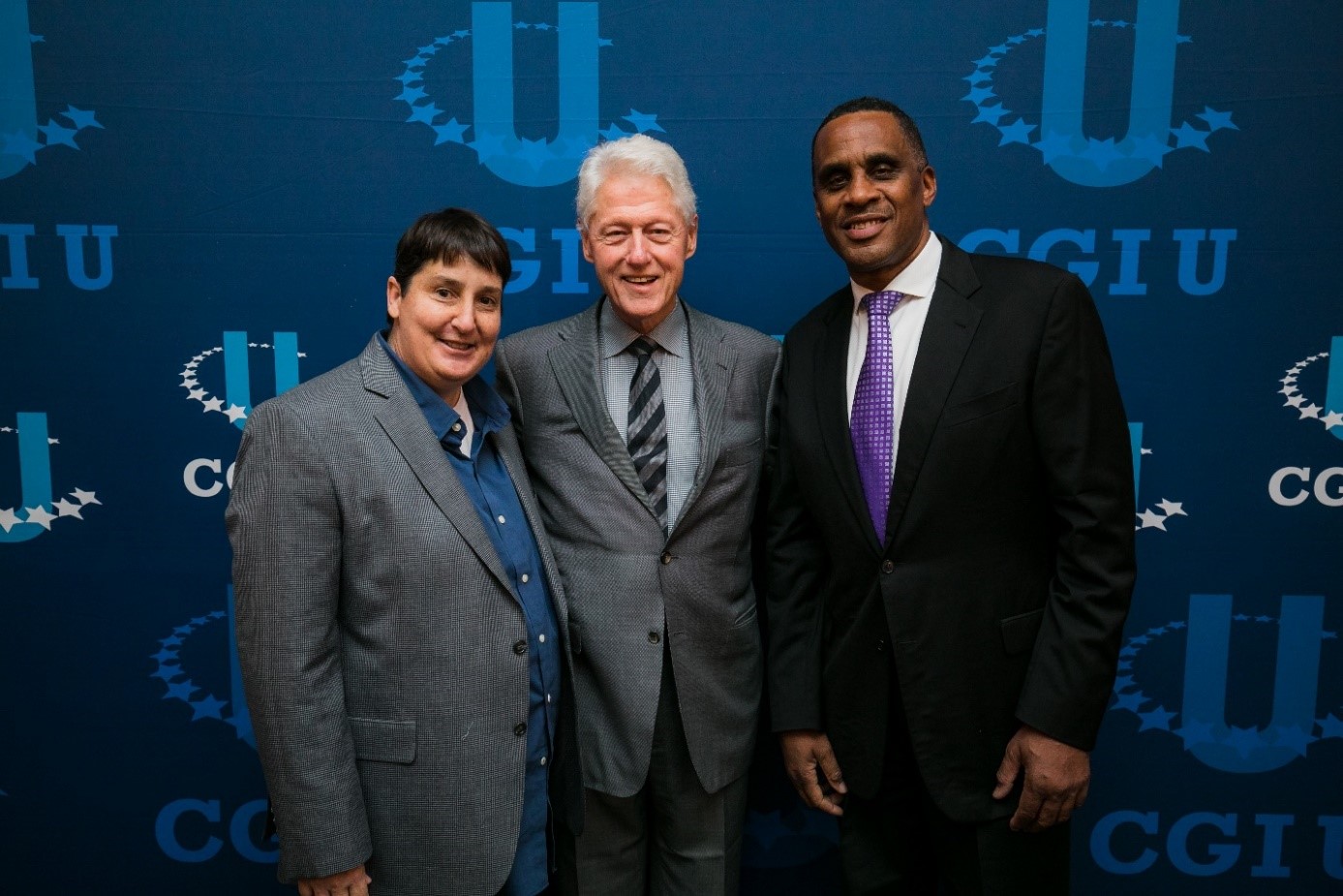 Professor Mary-Pat Stein with President Bill Clinton and another CGI-U guest standing in front of the CGI-U sign.
