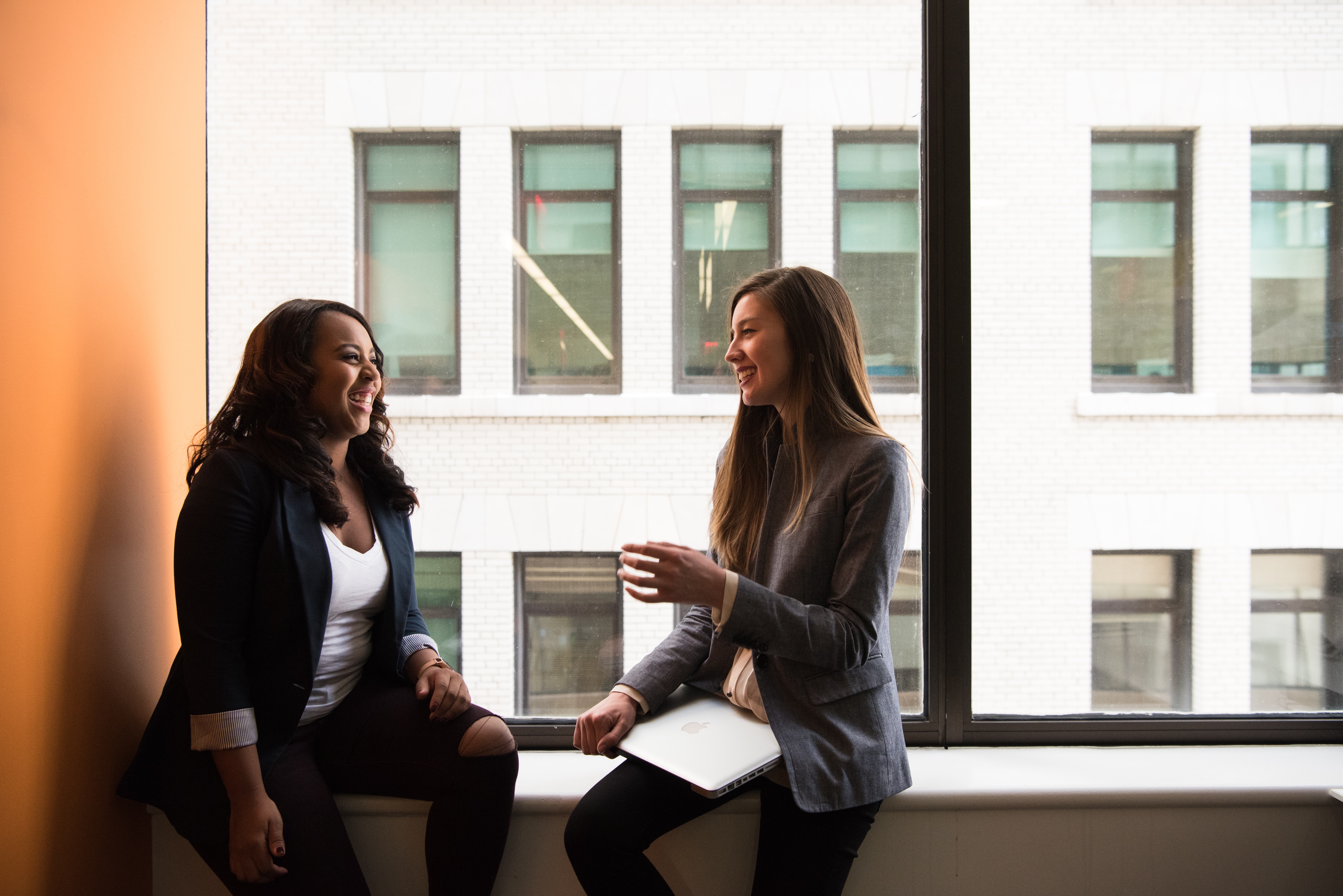 Two women sitting by the window laughing