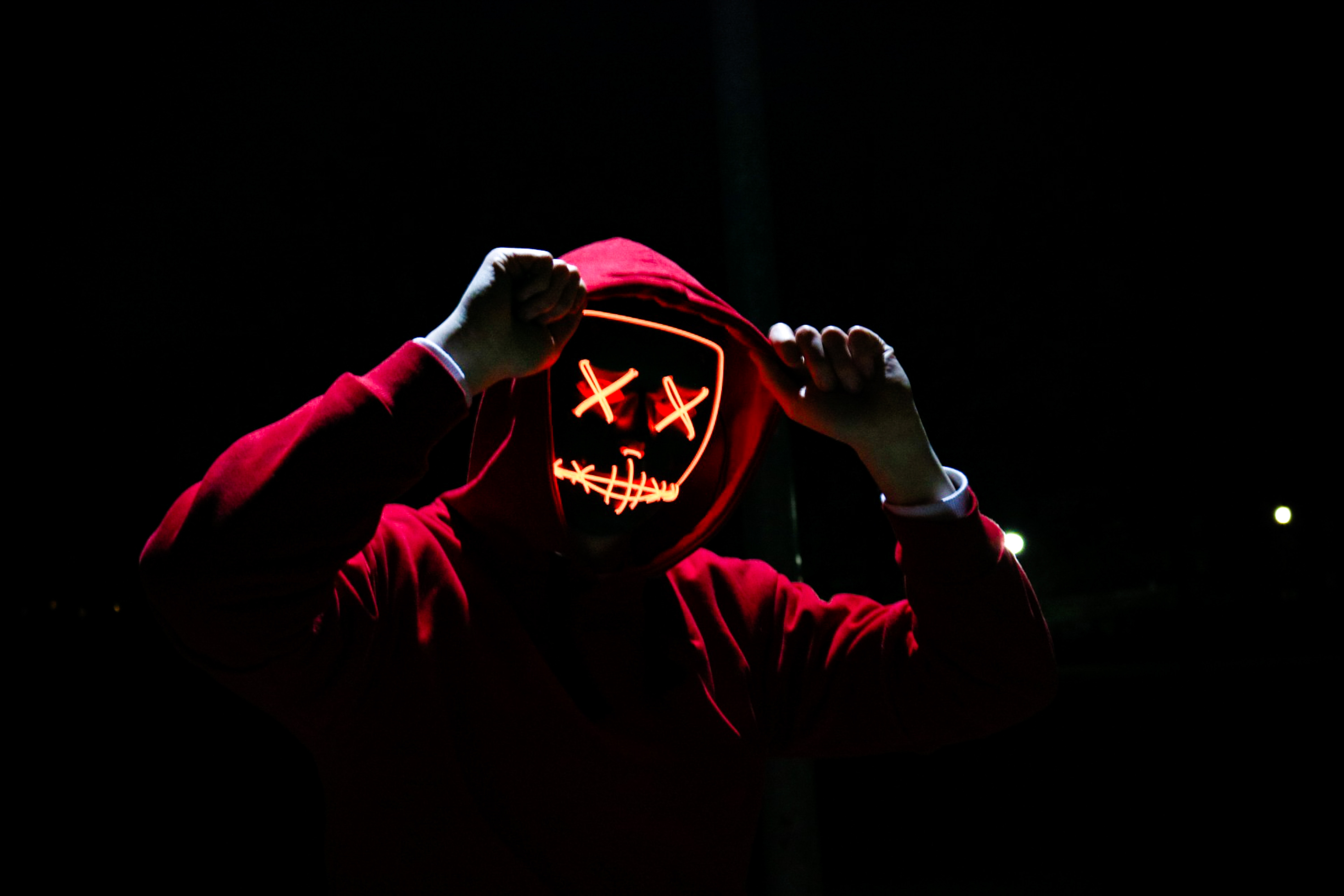 Guy with red hoodie and neon face in total dark background