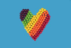 Variety of color balls on blue background forming a heart shape